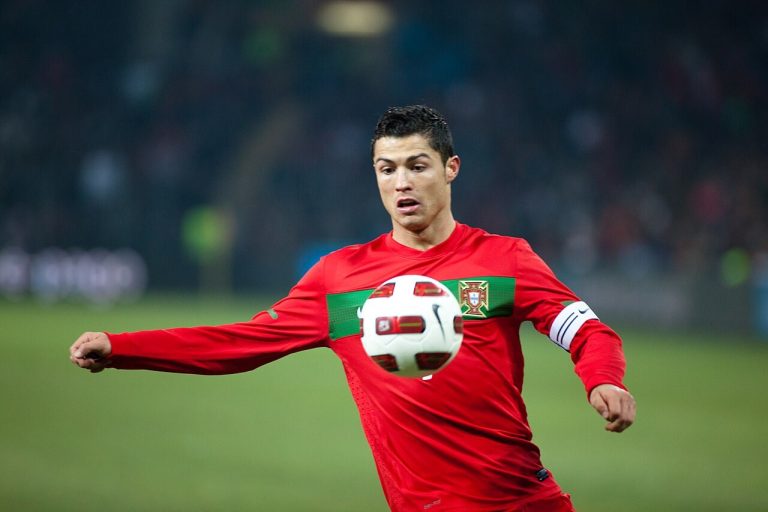 Cristiano Ronaldo in a red Portugal shirt controlling a football in a stadium