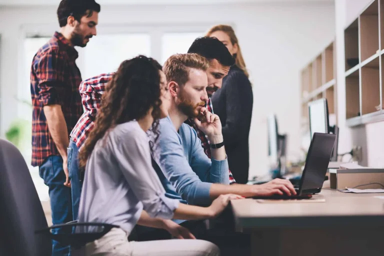 Two programmers cooperating at computers in an IT office