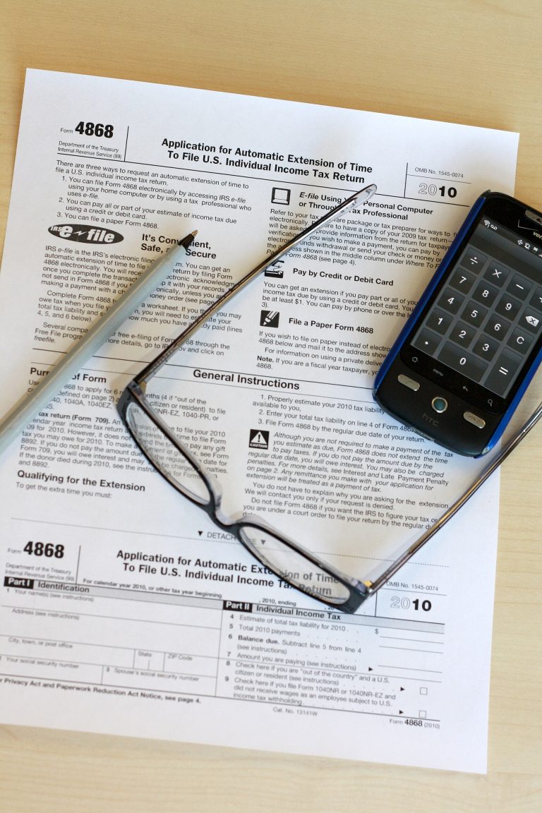 Paper financial form with a pen, glasses and a mobile phone